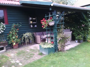 A house with a porch, outdoor seating, and various potted plants. - Apartment 'FeWo Hannehof' with Shared Terrace, Shared Garden and Wi-Fi (Tessin)