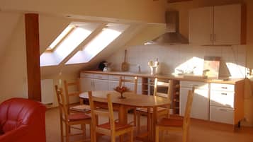 A kitchen with a dining area, featuring a skylight, wooden cabinets, and a red chair.