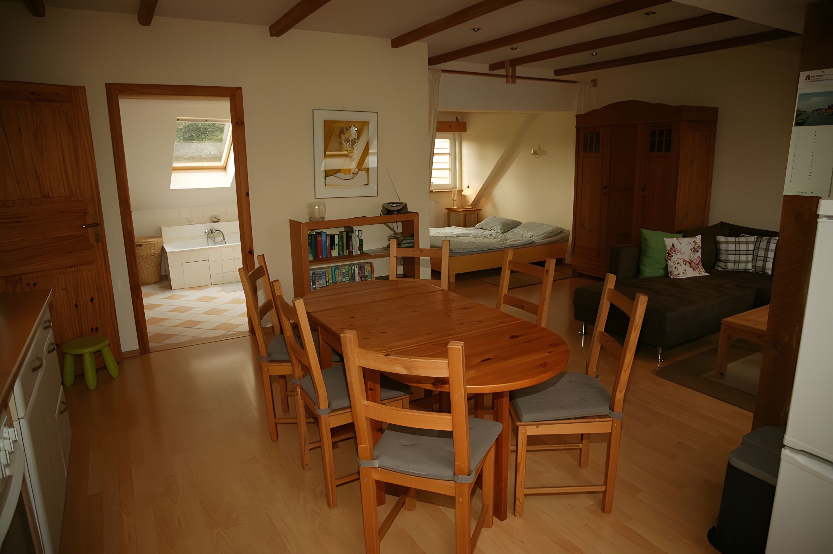 Une pièce chaleureuse avec une table à manger en bois, des chaises, un canapé et un lit.