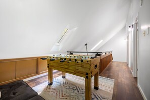 A room with a foosball table, a patterned rug, and a sloped ceiling with a skylight. - Newly Remodeled 3-bedroom escape nestled in the woods of Jim Thorpe Pennsylvania (Jim Thorpe)