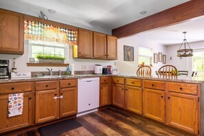 A kitchen with wooden cabinets, a coffee bar sign, a dishwasher, and a window with a plant. - Newly Remodeled 3-bedroom escape nestled in the woods of Jim Thorpe Pennsylvania (Jim Thorpe)