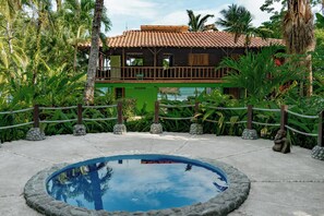 A two-story building with a tiled roof, surrounded by lush greenery and a swimming pool. - Casa Verde – Oceanfront Beach House in Matapalo (Matapalo)