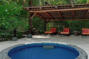 A pool area with a wooden pergola, two orange lounge chairs, and surrounding tropical vegetation. - Casa Verde – Oceanfront Beach House in Matapalo (Matapalo)