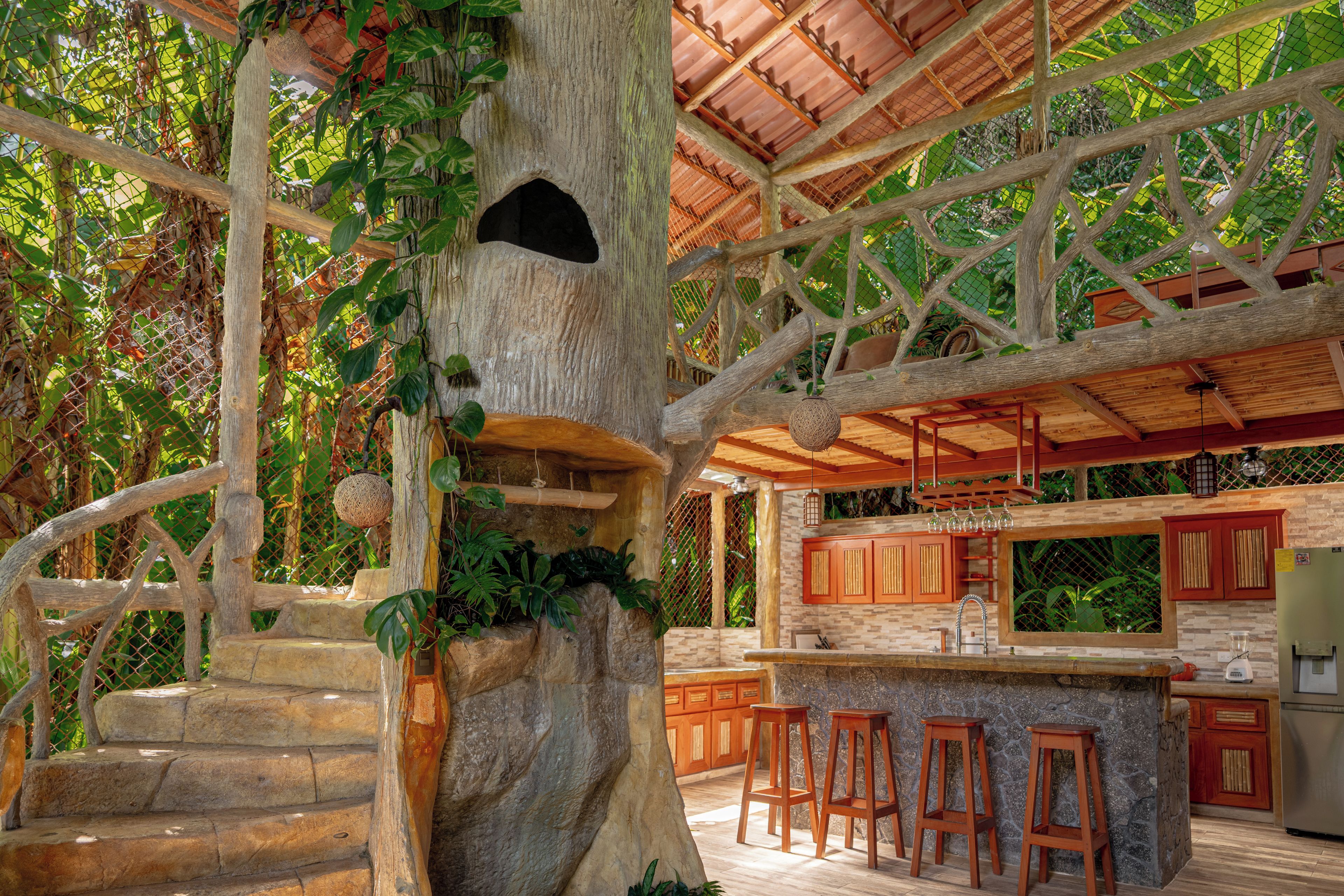 A treehouse with a wooden staircase, a kitchen area with a stone countertop, and a hanging basket.