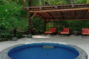 A pool area with a wooden pergola, two orange lounge chairs, and surrounding tropical vegetation. - Casa Aviari - Unique Rainforest Home in Matapalo (Matapalo)