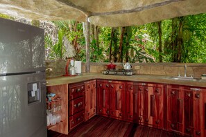 A kitchen with a stone countertop, wooden cabinets, and a stainless steel refrigerator. - Casa Contiki – Treetop Villa in Matapalo (Matapalo)