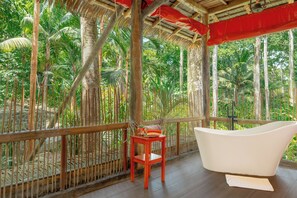 A wooden deck with a white bathtub, a small wooden stool, and a red cushion. - Casa Santa María – Secluded Beachfront Home (Matapalo)