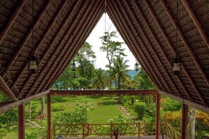 A covered outdoor area with a view of a lush garden and palm trees. - Casa Santa María – Secluded Beachfront Home (Matapalo)