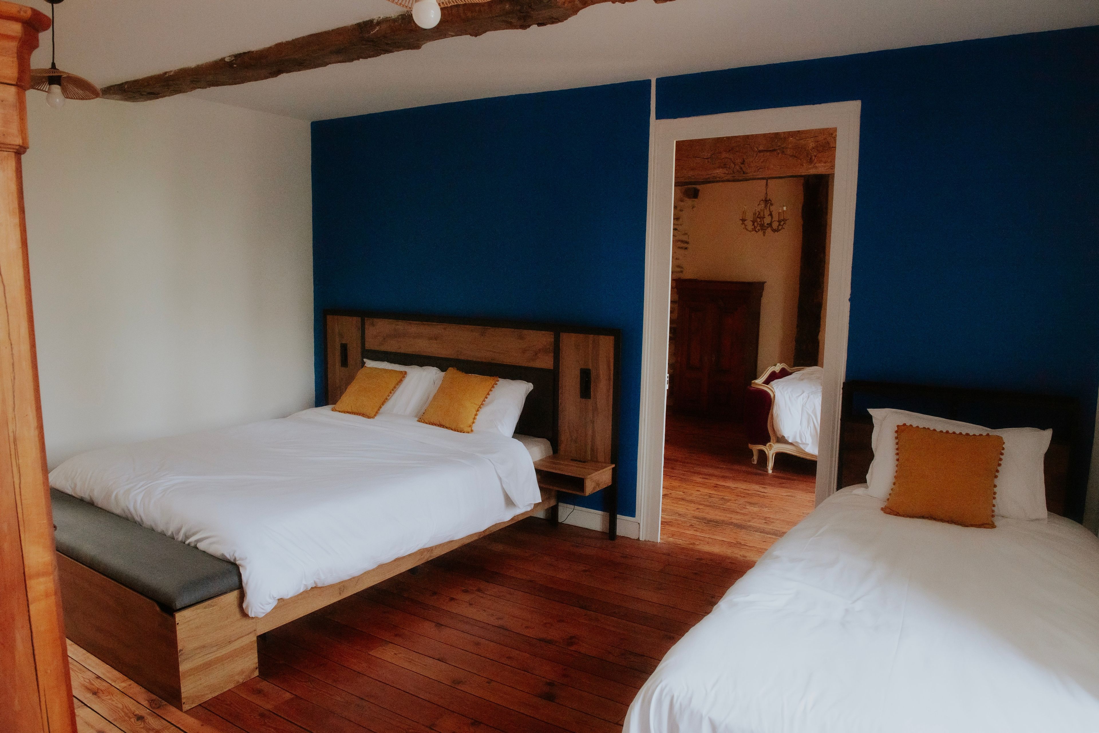 Une chambre avec deux lits, un plancher en bois et un mur d’accent bleu.