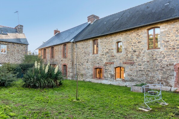 Un bâtiment en pierre doté de nombreuses fenêtres et d’un toit en pente.