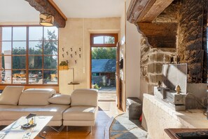 Un salon spacieux doté d’une grande fenêtre, d’une cheminée en pierre et d’un canapé moderne.
