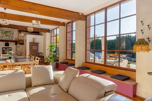 Un intérieur chaleureux avec un coin repas, un banc pour s’asseoir près d’une grande fenêtre et une plante en pot.