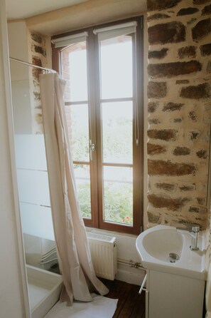 Un bany amb dutxa, un lavabo i una finestra.