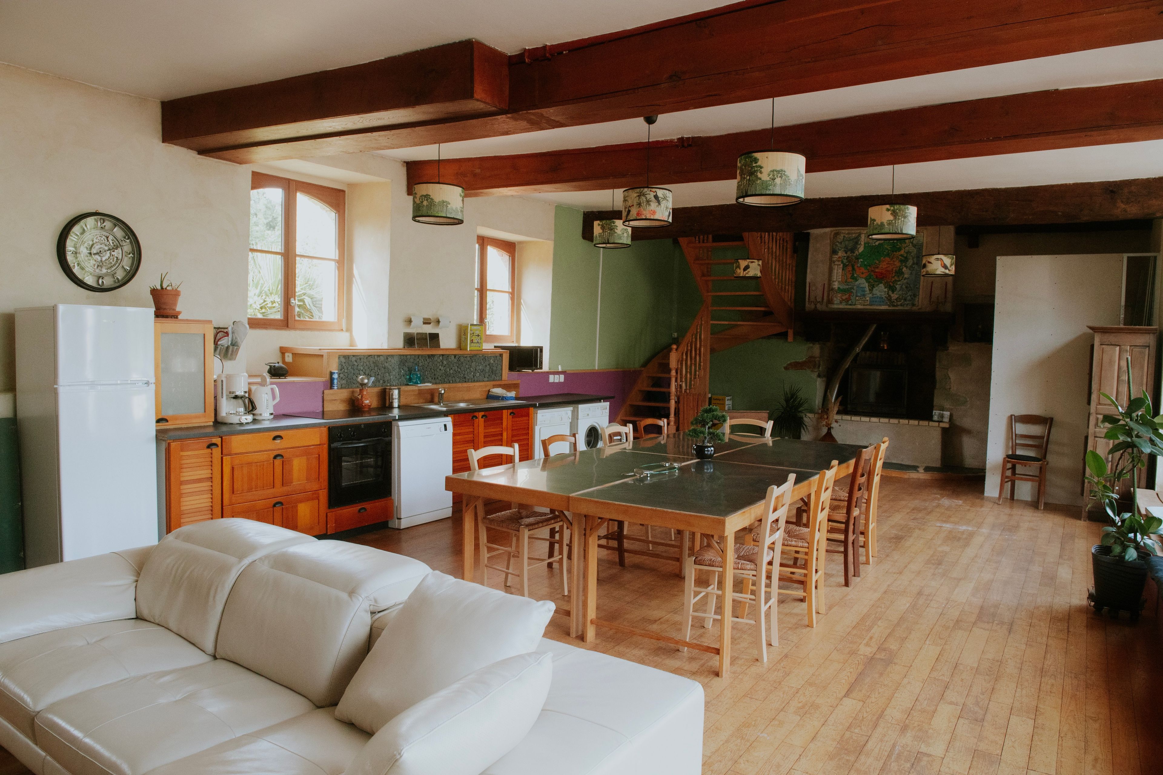 A spacious kitchen with wooden beams, a dining area with a table and chairs, and a cozy living room with a sofa.