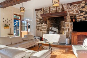 Un salon avec une cheminée en pierre, un canapé en cuir et un téléviseur.