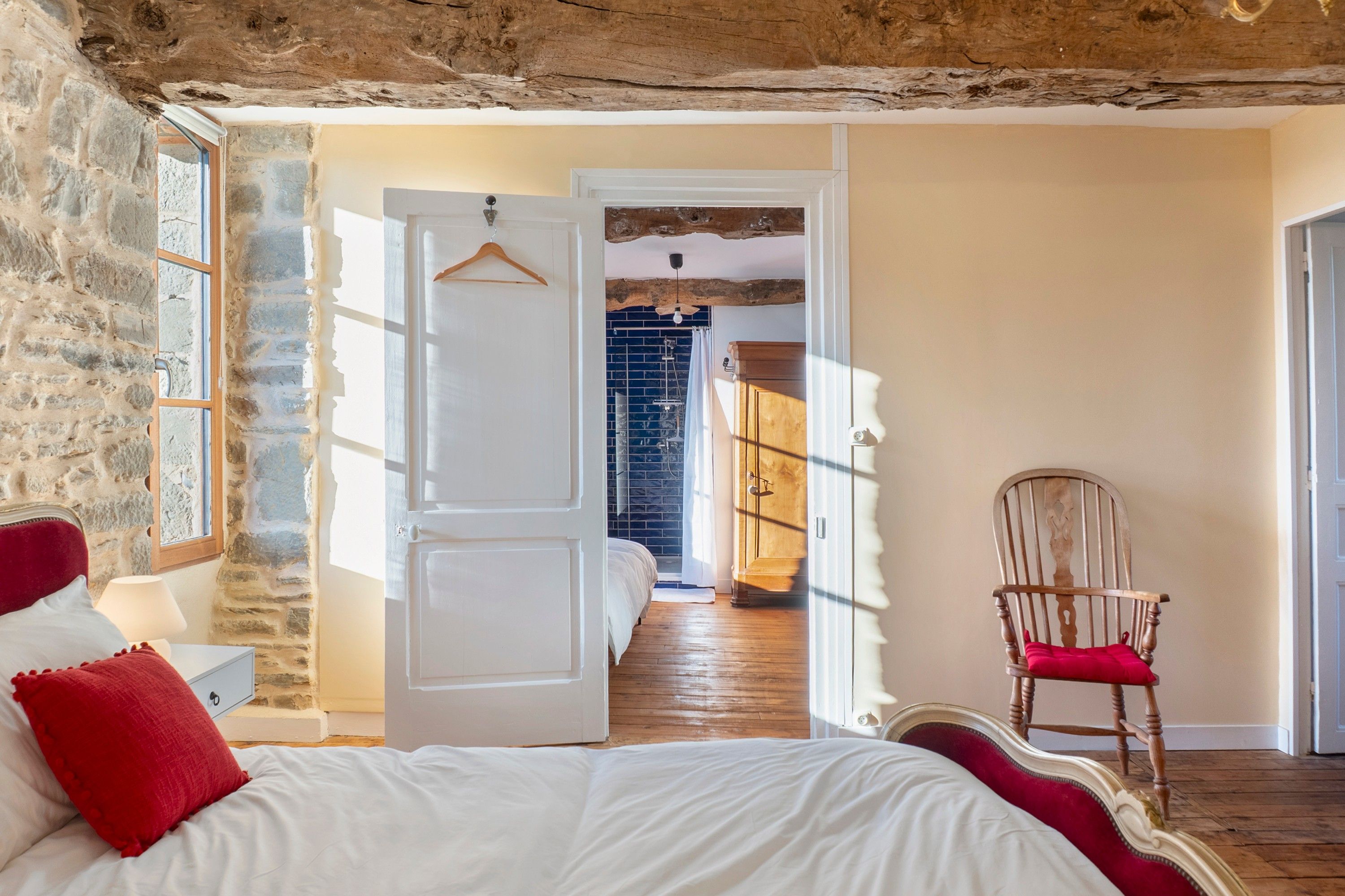 Une chambre à coucher avec un lit, une chaise et une porte donnant sur une autre pièce.