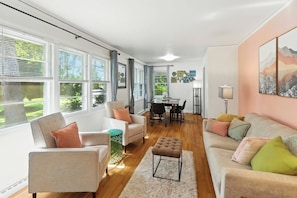 A modern living room with a dining area, large windows, and a view of greenery. - Charming Ranch, 2BR Oasis Downtown Travelers Rest (Travelers Rest)