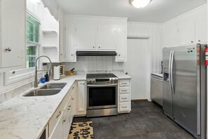 A kitchen with white cabinets, a stainless steel refrigerator, a stove, and a sink. - Charming Ranch, 2BR Oasis Downtown Travelers Rest (Travelers Rest)