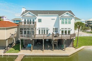 A two-story waterfront house with a balcony, a dock, and a small pool. - Spacious Bayfront Retreat - Pet Friendly with Private Fishing Pier (Galveston)