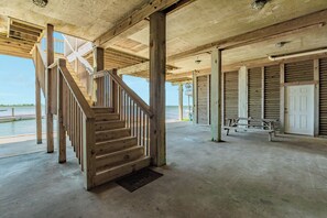 A wooden staircase leading to an upper level, a concrete floor, and a view of the water. - Spacious Bayfront Retreat - Pet Friendly with Private Fishing Pier (Galveston)