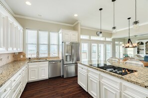 A kitchen with white cabinetry, stainless steel appliances, a granite countertop, and a view through large windows. - Spacious Bayfront Retreat - Pet Friendly with Private Fishing Pier (Galveston)