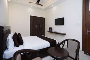 A hotel room with a bed, a chair, a TV, and a wardrobe.