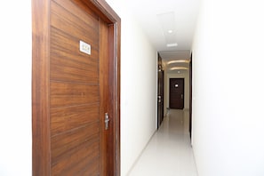 Un pasillo con puerta de madera y pared blanca.