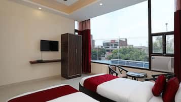 Quarto de hotel com duas camas, televisão, guarda-roupa, janela com vista para a cidade e ar condicionado.