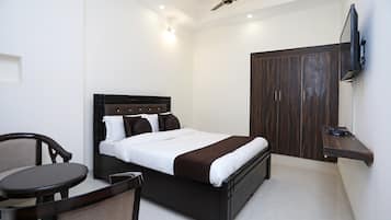 Quarto com cama, cadeira, mesa, guarda-roupa e ventilador de teto.