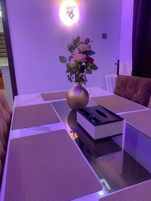 Ein Esstisch mit Blumen in einer Vase, einer Papprobox und einem Stuhl.