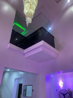 Ein modernes Interieur mit Balkon, einer Kristallleuchtre und einem Ventilator.