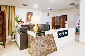 Una mesa de recepción con frente de mármol, una computadora y una lámpara.