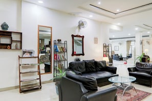 Uma sala de estar moderna com um sofá de couro, uma mesa de centro de vidro e uma estante.