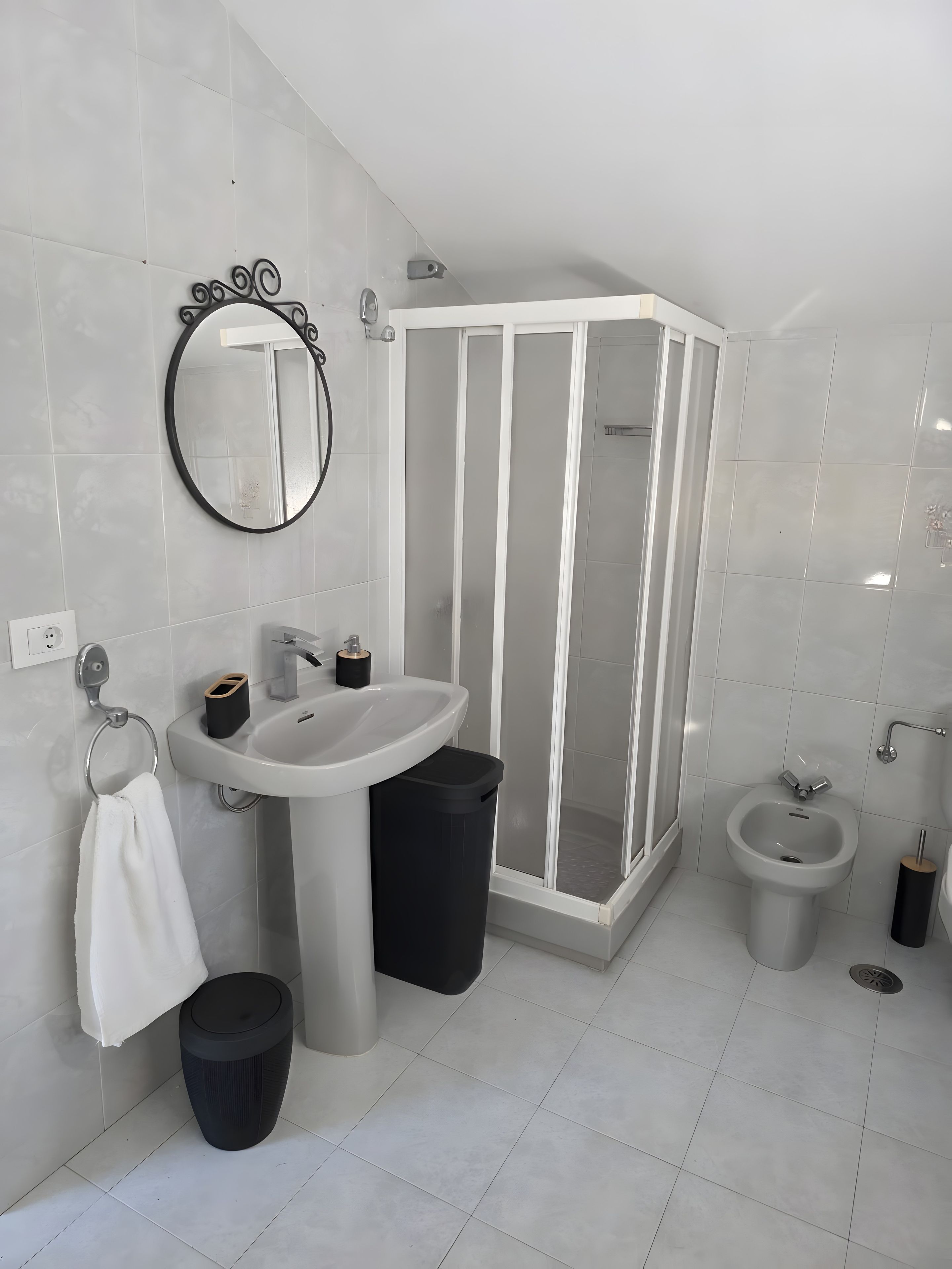 Een moderne badkamer met een wastafel, spiegel, toilet, bidet en douchecabine.