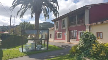 Un edificio de dos pisos con un balcón, una palmera y una vitrina de vidrio con artículos.