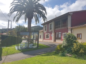 Un edificio de dos pisos con un balcón, una palmera y una vitrina de vidrio con artículos.