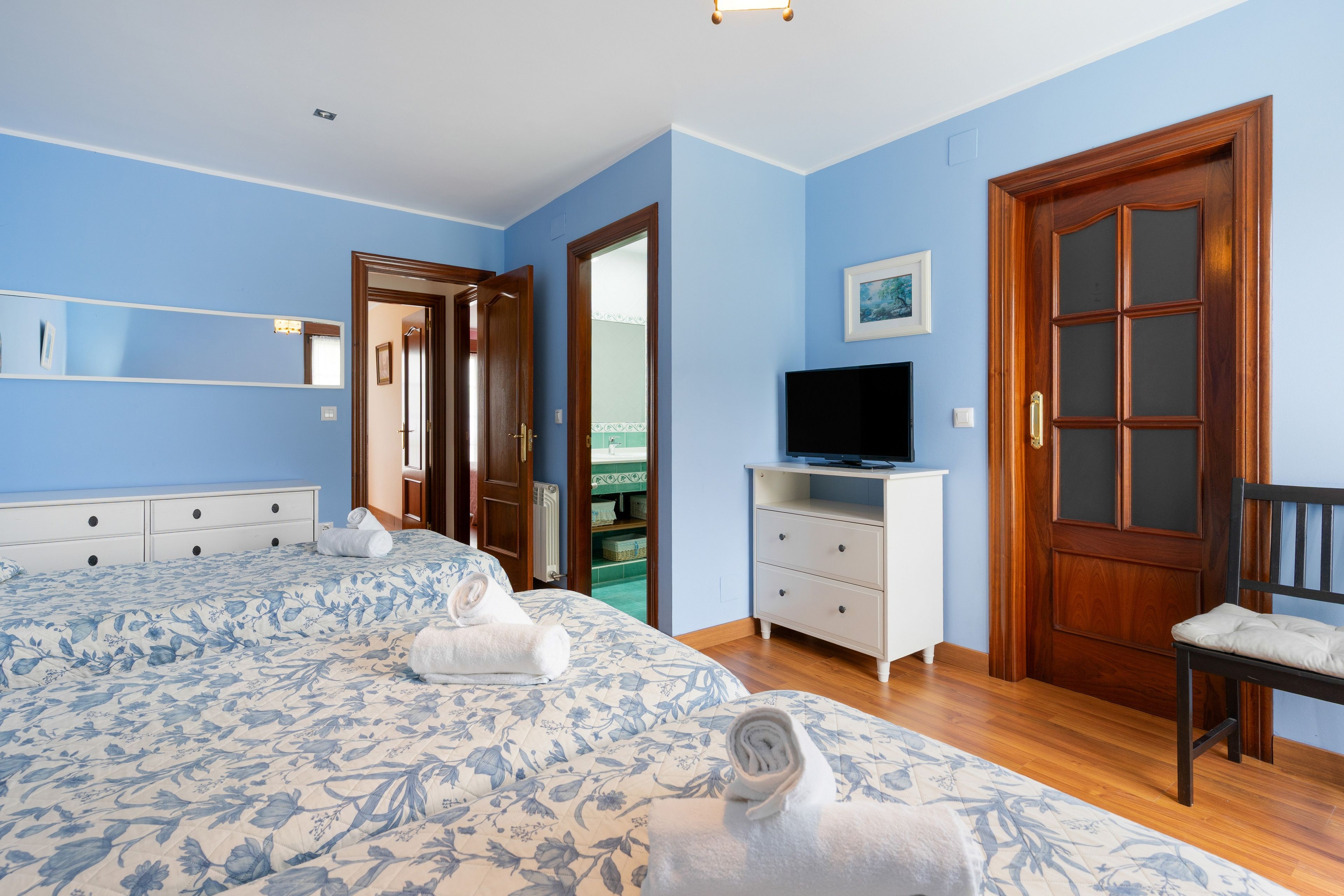 Un dormitorio con una cama grande, televisor, cómoda y puerta.