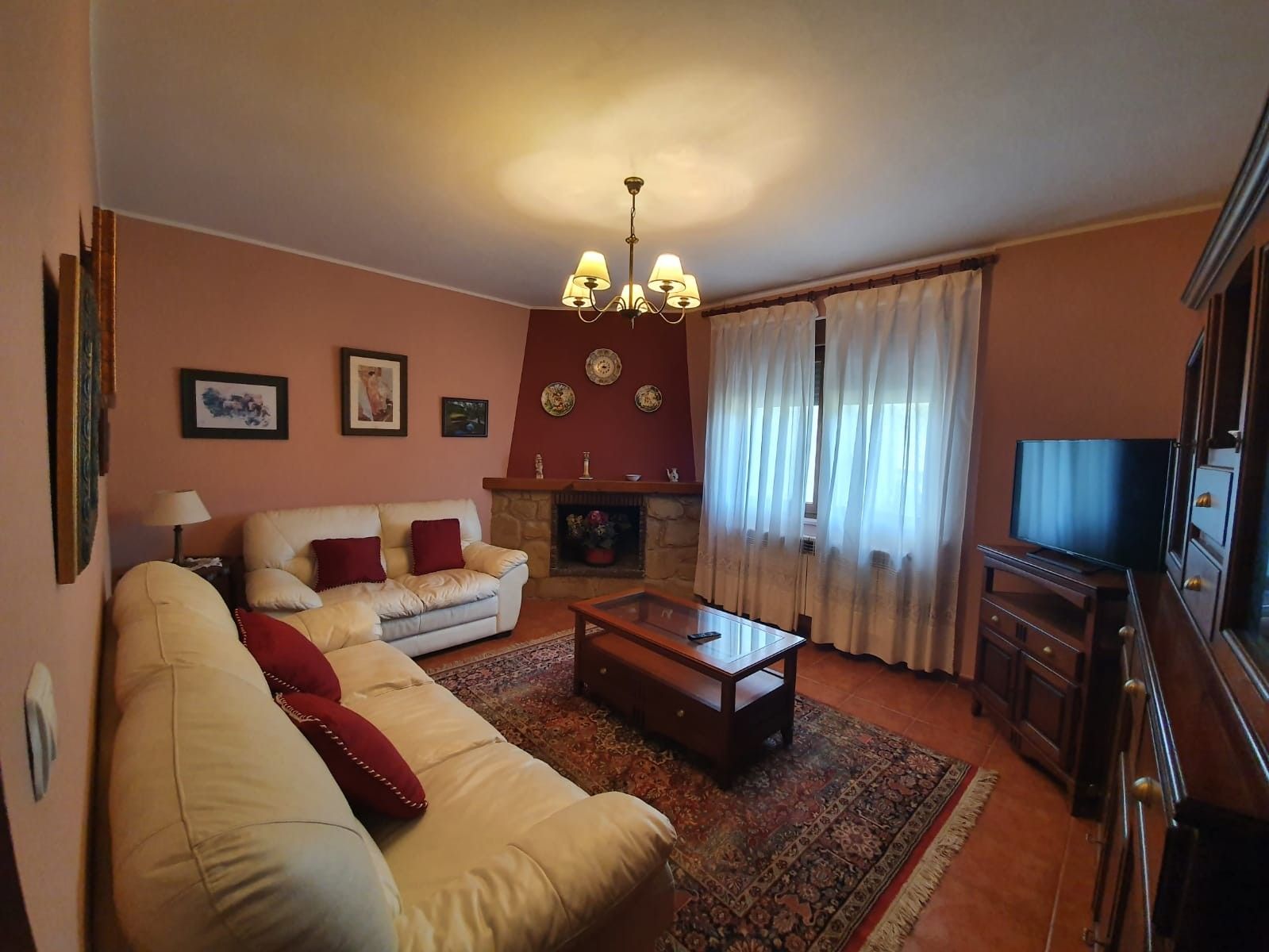 Una sala de estar con sofá, mesa de centro, chimenea, televisor y candelabro.