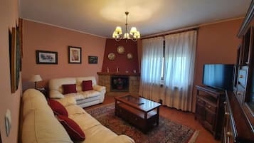 Una sala de estar con sofá, mesa de centro, chimenea, televisor y candelabro.