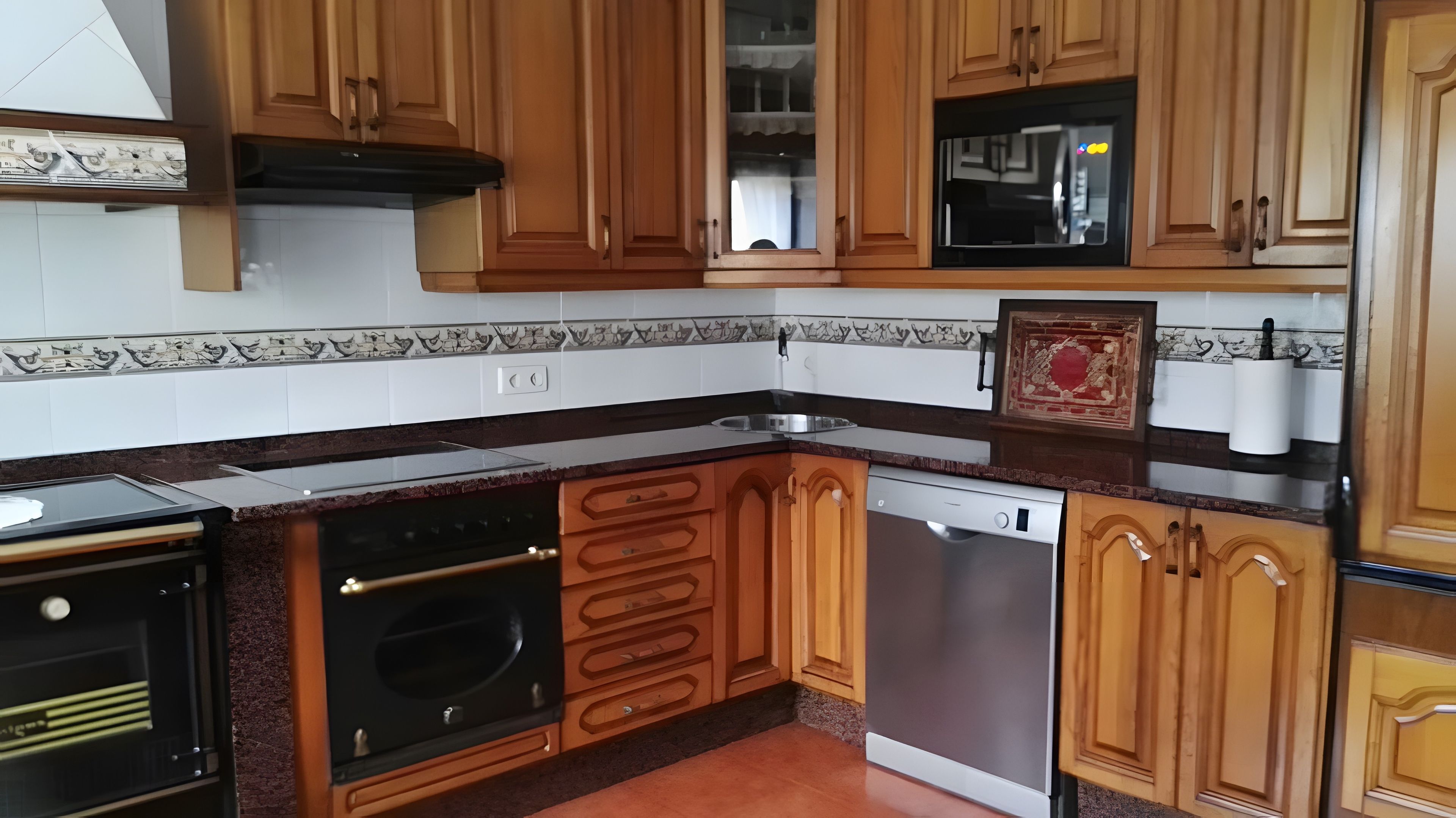 Una cocina con armarios de madera, un microondas negro y un lavavajillas.