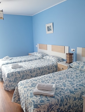 Habitación de hotel con dos camas, una mesita de noche y una lámpara de pared.