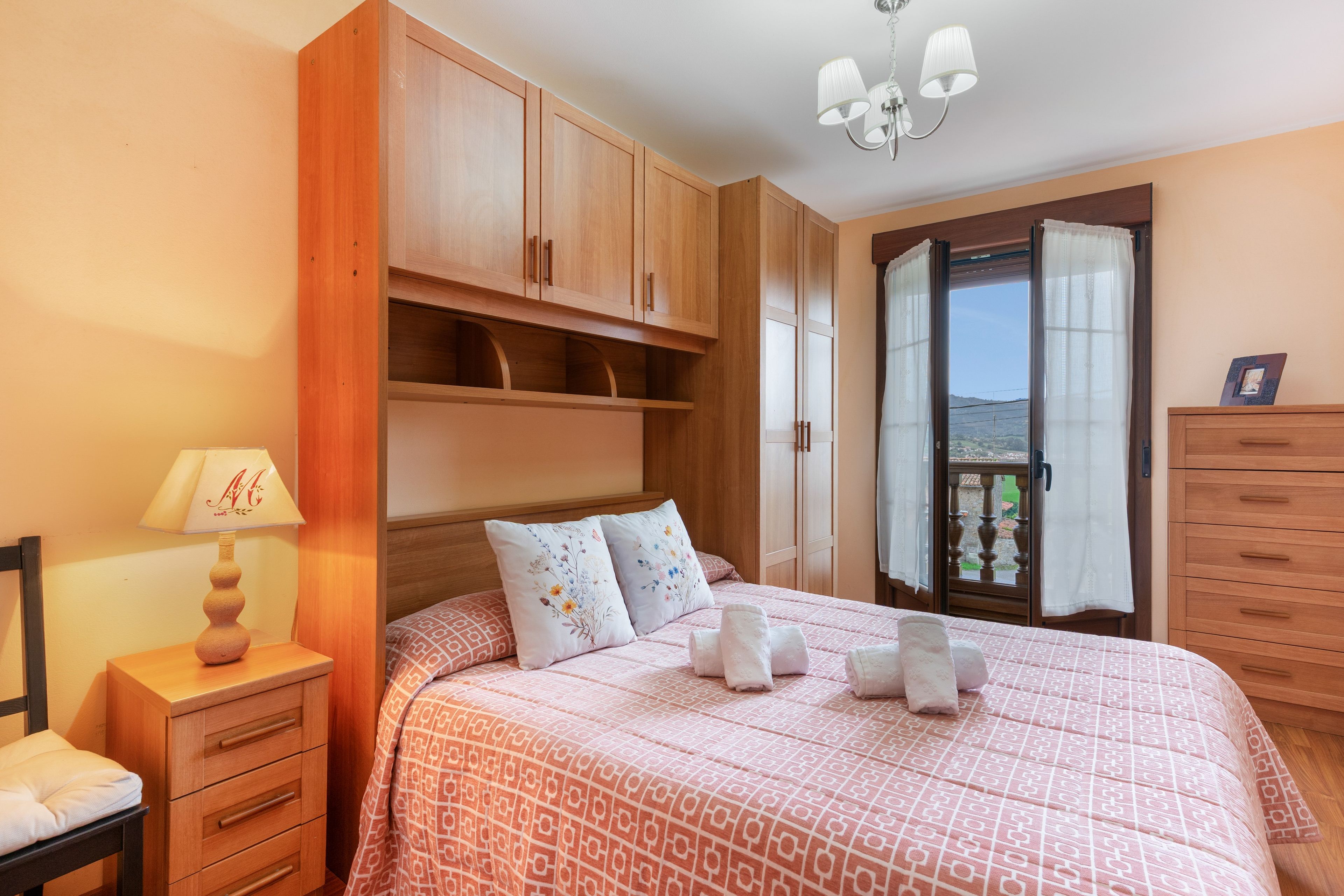 Une chambre à coucher avec un lit, des tables de chevet, une commode et une fenêtre donnant sur un beau paysage.