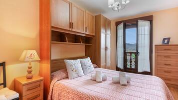Une chambre à coucher avec un lit, des tables de chevet, une commode et une fenêtre donnant sur un beau paysage.