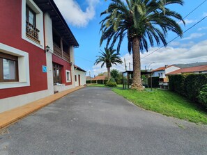 A street with a red building, a palm tree, and a clear sky. - Country House 'Casa Rural Loli' with Private Pool, Garden, Nature and Wi-Fi in Asturias (Bedriñana)