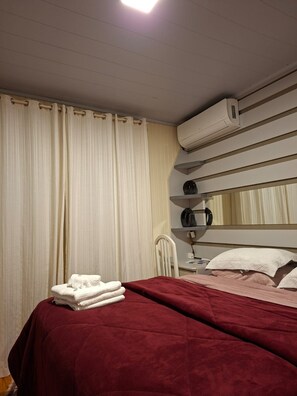 A hotel room with a bed, a chair, a desk, and an air conditioning unit. - New Listing (Bento Gonçalves)