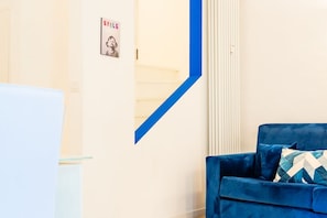 A room with a blue sofa, a white radiator, and a poster on the wall. - [Cozy] Blue Velvet Loft* (Torino)