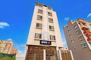 Un edificio de hotel con varios balcones, un cartel que indica que es el Hotel OYO Shanti Niketan y una entrada con portones.