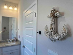 A bathroom with a white door, a mirror, and a wall-mounted decorative anchor. - Spacious 3 bedroom house + 1 bedroom Mother-in-law suite with its own entrance (Port St. Joe)