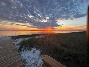 Un atardecer sobre una playa con un paseo marítimo de madera que lleva al agua.