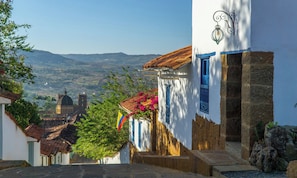 Eine enge Straße mit traditioneller Architektur, Steinstufen und Blick auf weit entfernte Hügel.